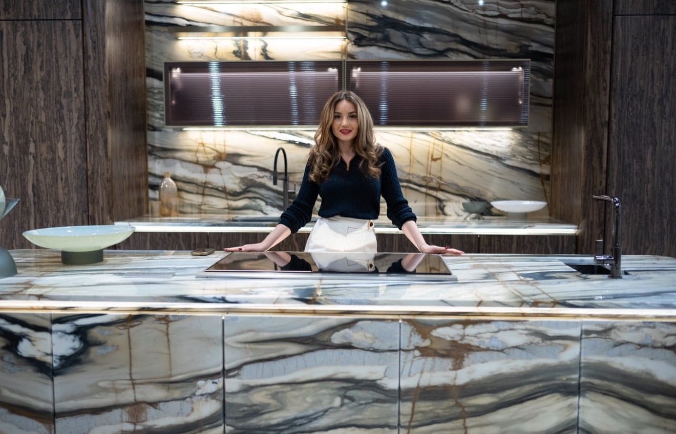 Denisa Popovici, founder of Nisi Maison, standing at a marble kitchen island